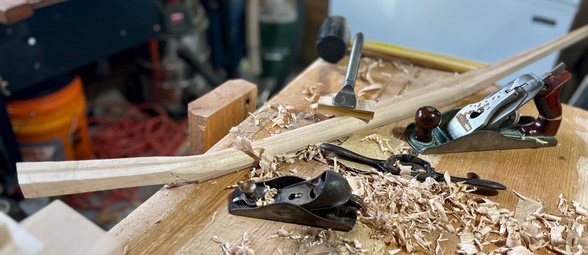 An in-progress banjo neck on a work bench with hand tools